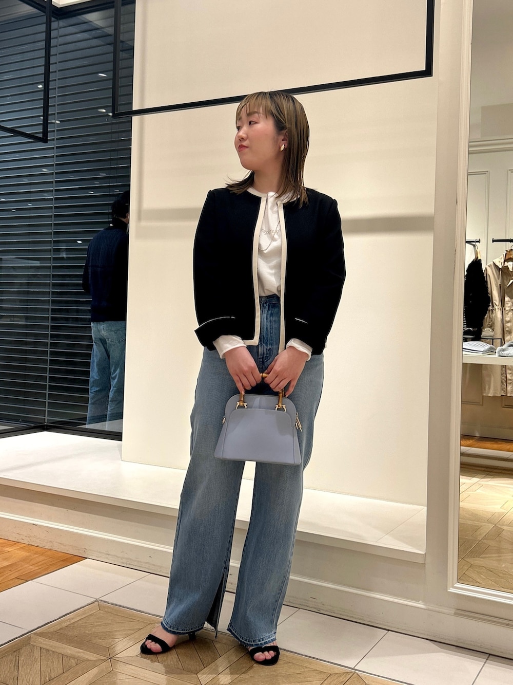 ブラック系のノーカラージャケット、ホワイト系のTシャツ/カットソー、ブルー系のデニムパンツを着用したレディースの冬コーディネートの3枚目の写真