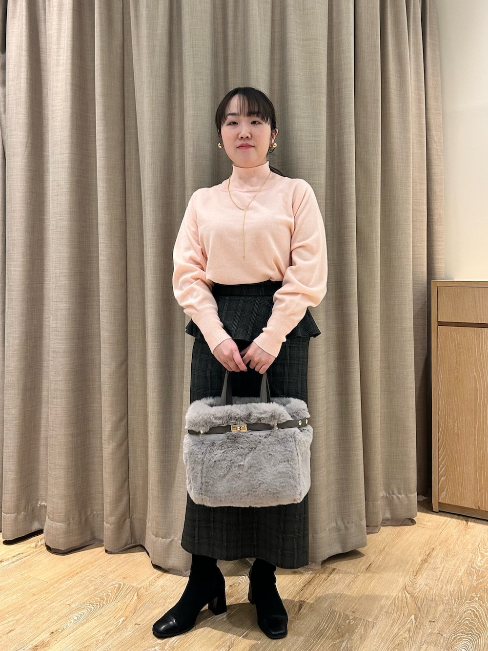 ピンク系のニット/セーター、ブラック系のスカート、ベージュ系のトートバッグを着用したレディースの冬コーディネートの5枚目の写真