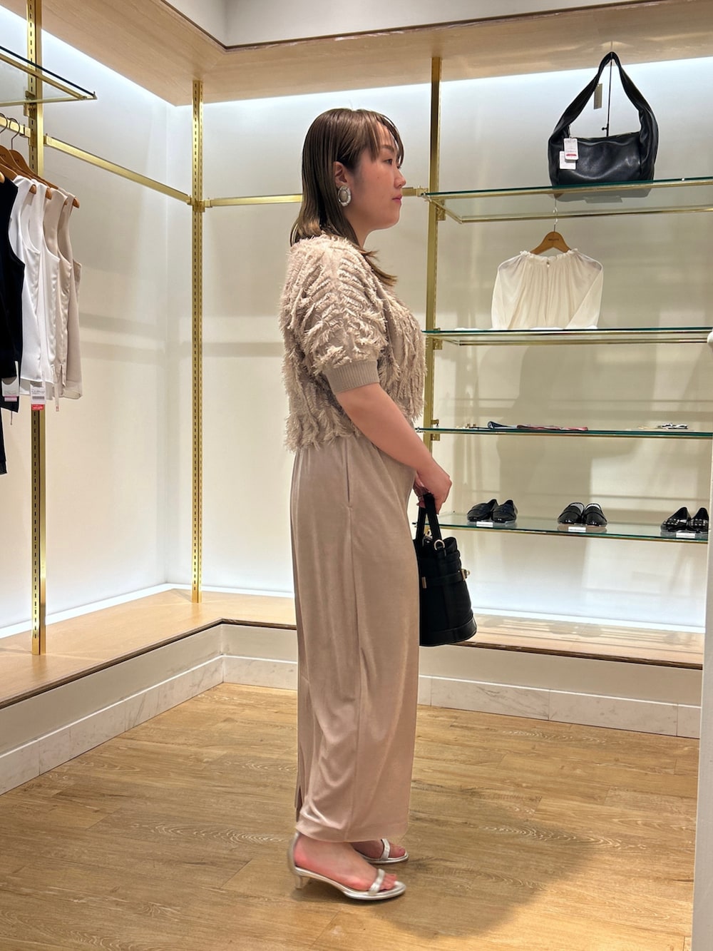 ベージュ系のニット/セーター、ベージュ系のスカート、ブラック系のショルダーバッグを着用したレディースの夏コーディネートの4枚目の写真