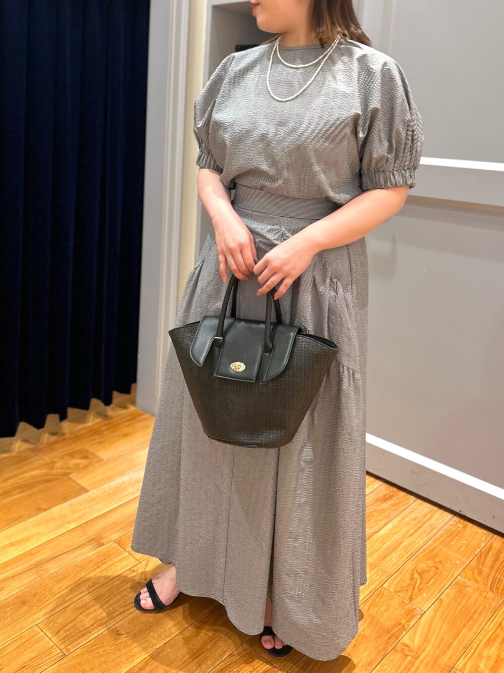 グレー系のシャツ/ブラウス、グレー系のスカート、ブラック系のかごバッグを着用したレディースの夏コーディネートの6枚目の写真