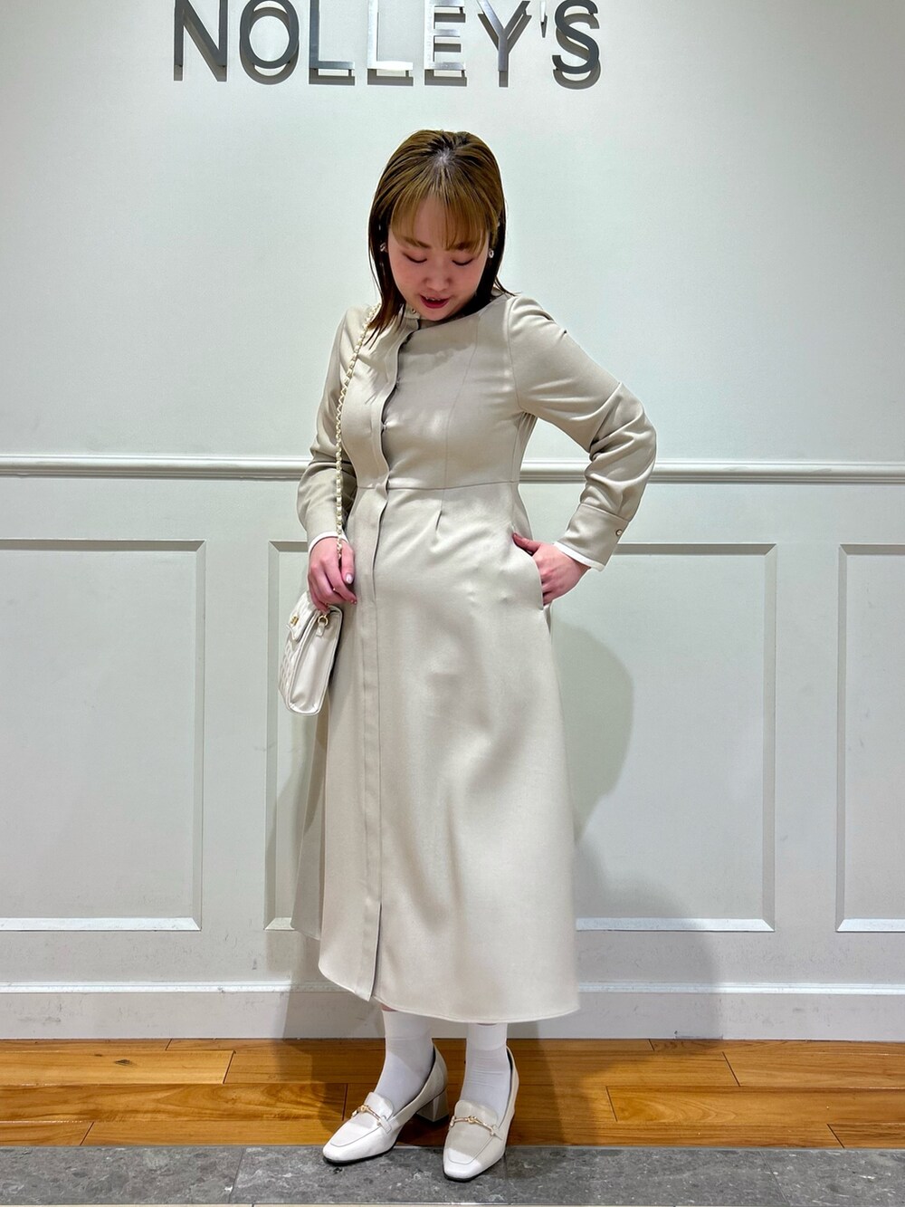 ベージュ系のワンピース、ホワイト系のショルダーバッグ、ホワイト系のイヤリングを着用したレディースの冬コーディネートの7枚目の写真