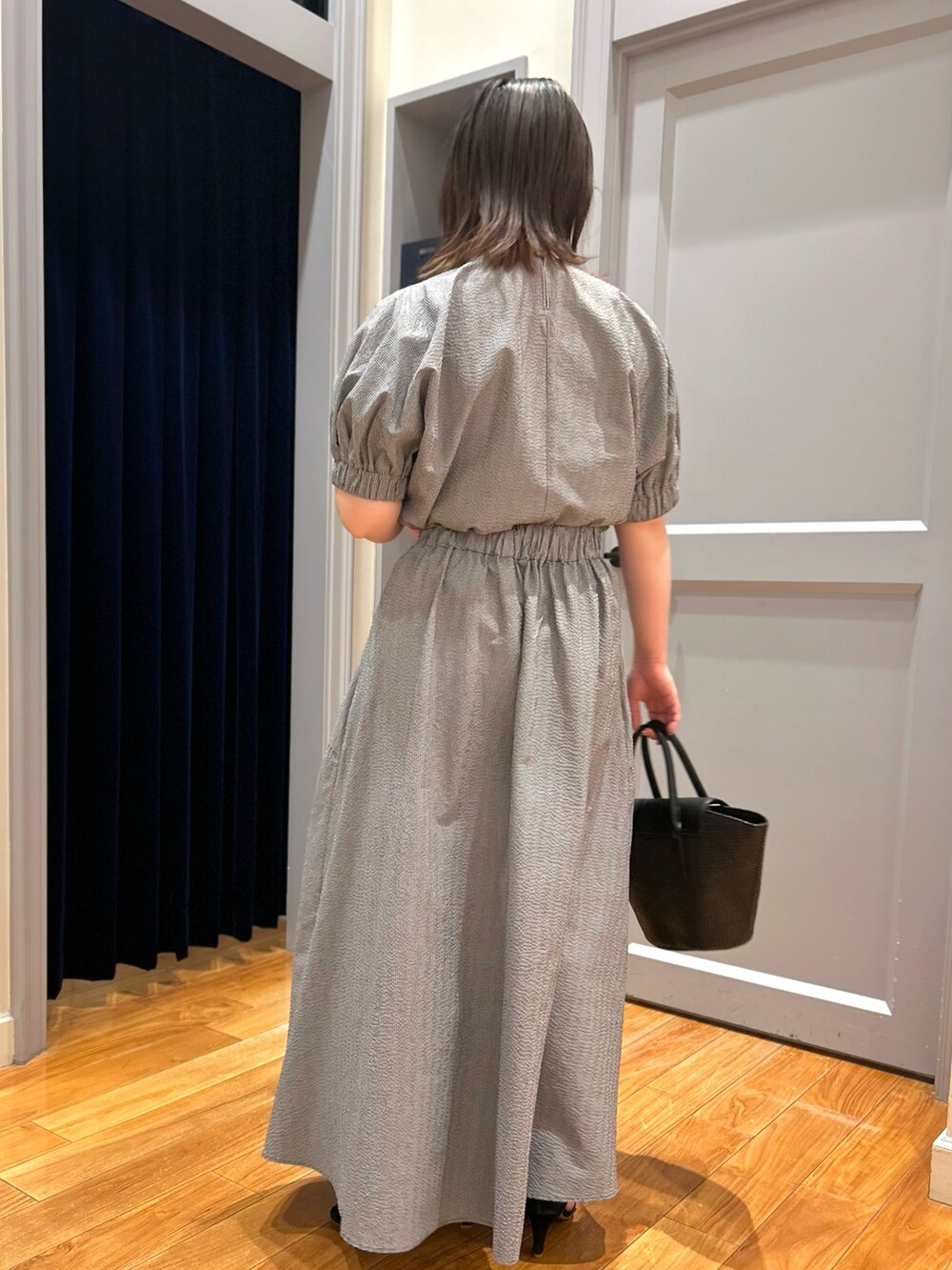 グレー系のシャツ/ブラウス、グレー系のスカート、ブラック系のかごバッグを着用したレディースの夏コーディネートの3枚目の写真