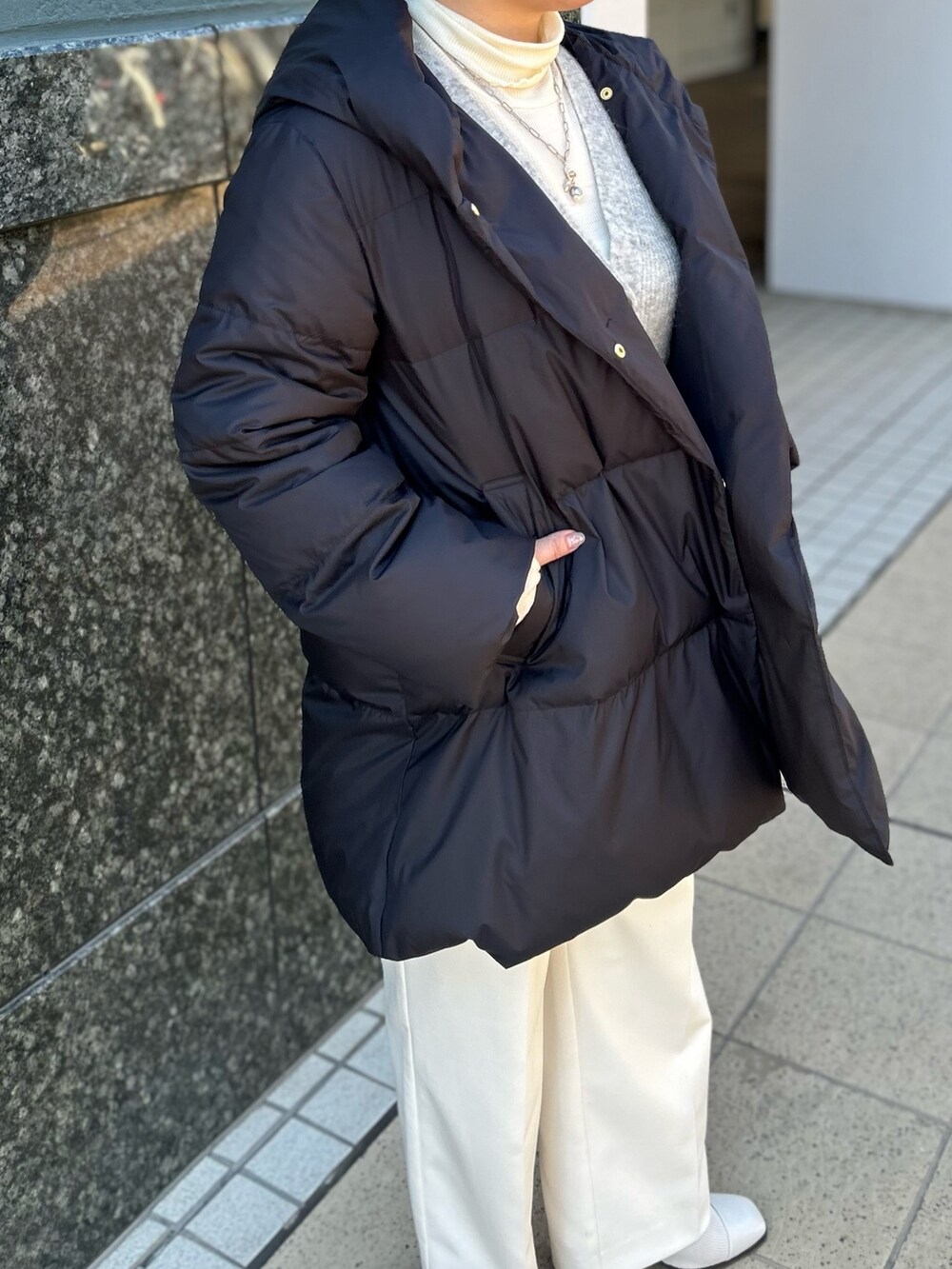 ブラック系のダウンジャケット/コート、グレー系のカーディガン/ボレロ、ホワイト系のTシャツ/カットソーを着用したレディースの冬コーディネートの7枚目の写真
