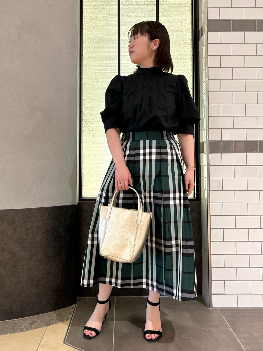 ブラック系のシャツ/ブラウス、グリーン系のスカート、ホワイト系のトートバッグを着用したレディースの夏コーディネートの2枚目の写真