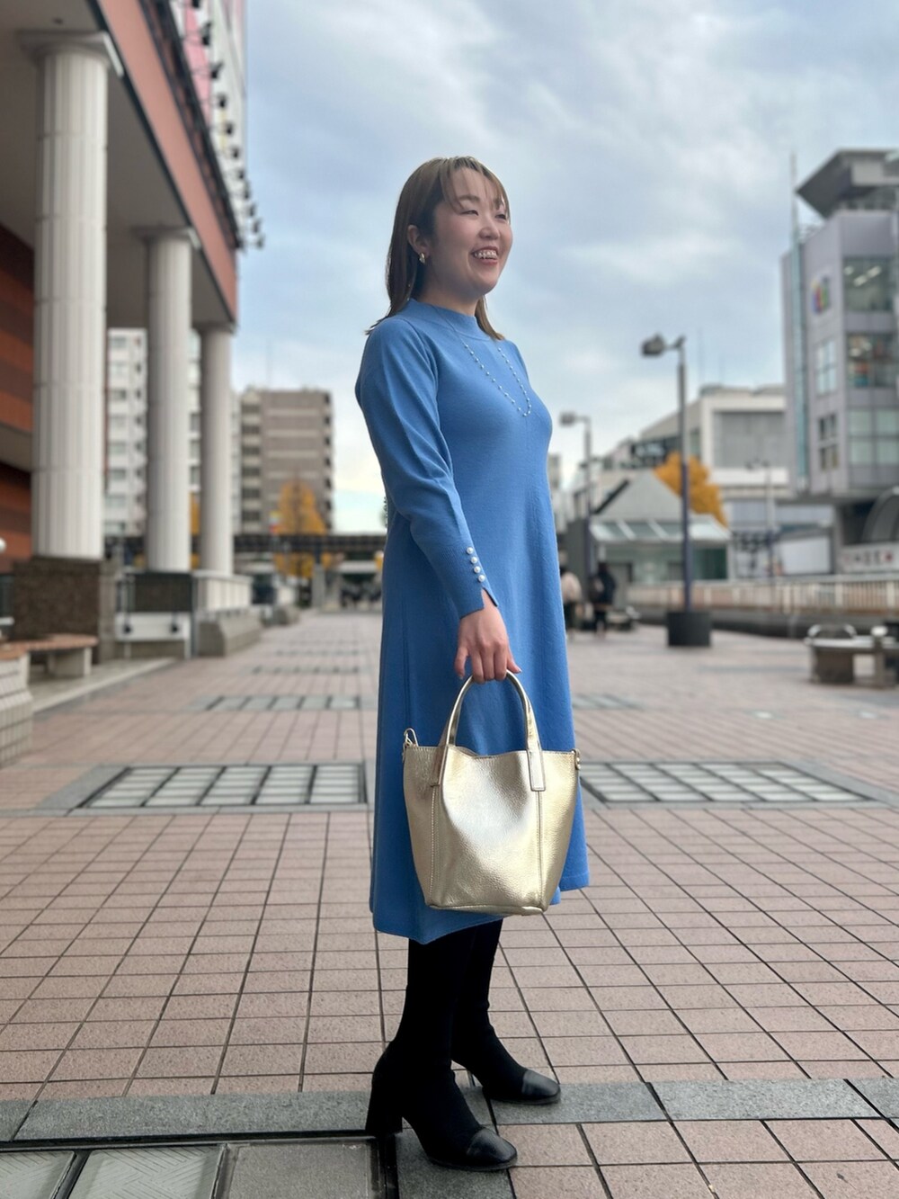 ブルー系のワンピース、ゴールド系のトートバッグ、ゴールド系のイヤリングを着用したレディースの冬コーディネートの5枚目の写真