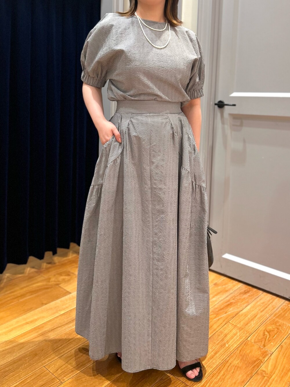 グレー系のシャツ/ブラウス、グレー系のスカート、ブラック系のかごバッグを着用したレディースの夏コーディネートの7枚目の写真