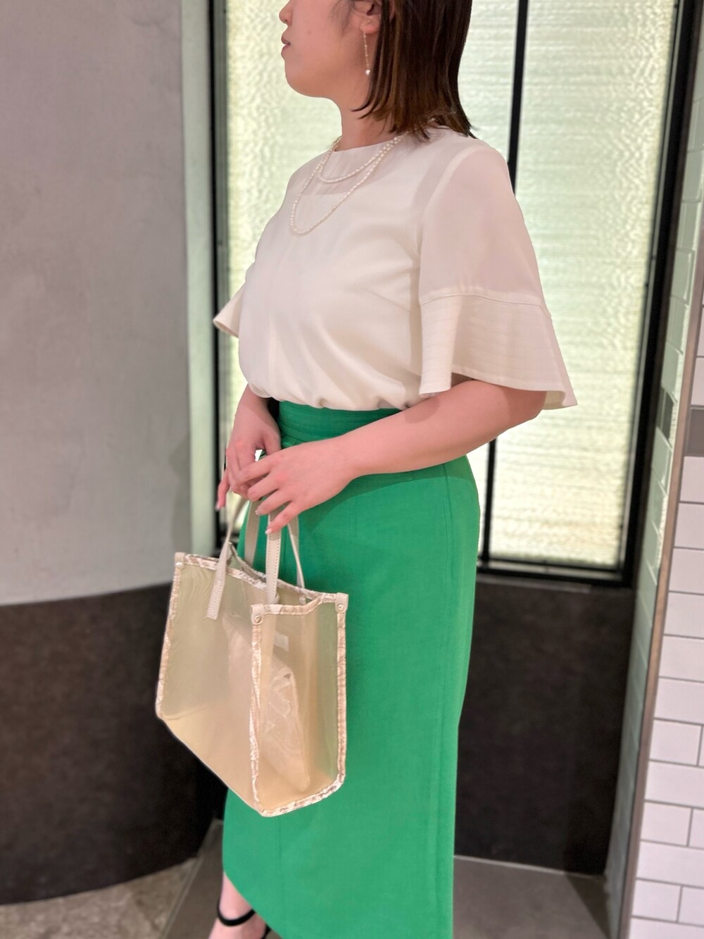 ベージュ系のトートバッグ、ホワイト系のシャツ/ブラウス、グリーン系のスカートを着用したレディースの春コーディネートの9枚目の写真