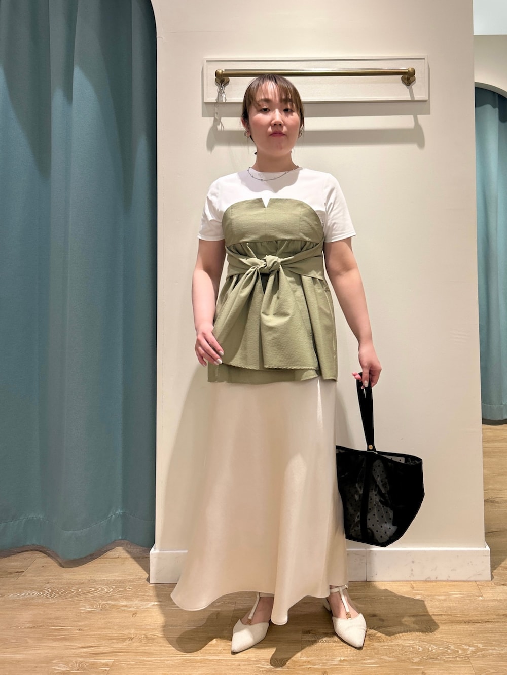 グリーン系のTシャツ/カットソー、ホワイト系のスカート、ブラック系のトートバッグを着用したレディースの夏コーディネートの2枚目の写真