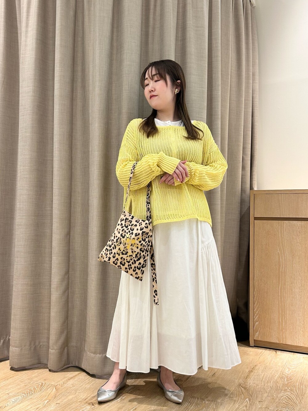 イエロー系のニット/セーター、ホワイト系のTシャツ/カットソー、ホワイト系のスカートを着用したレディースの春コーディネートの5枚目の写真