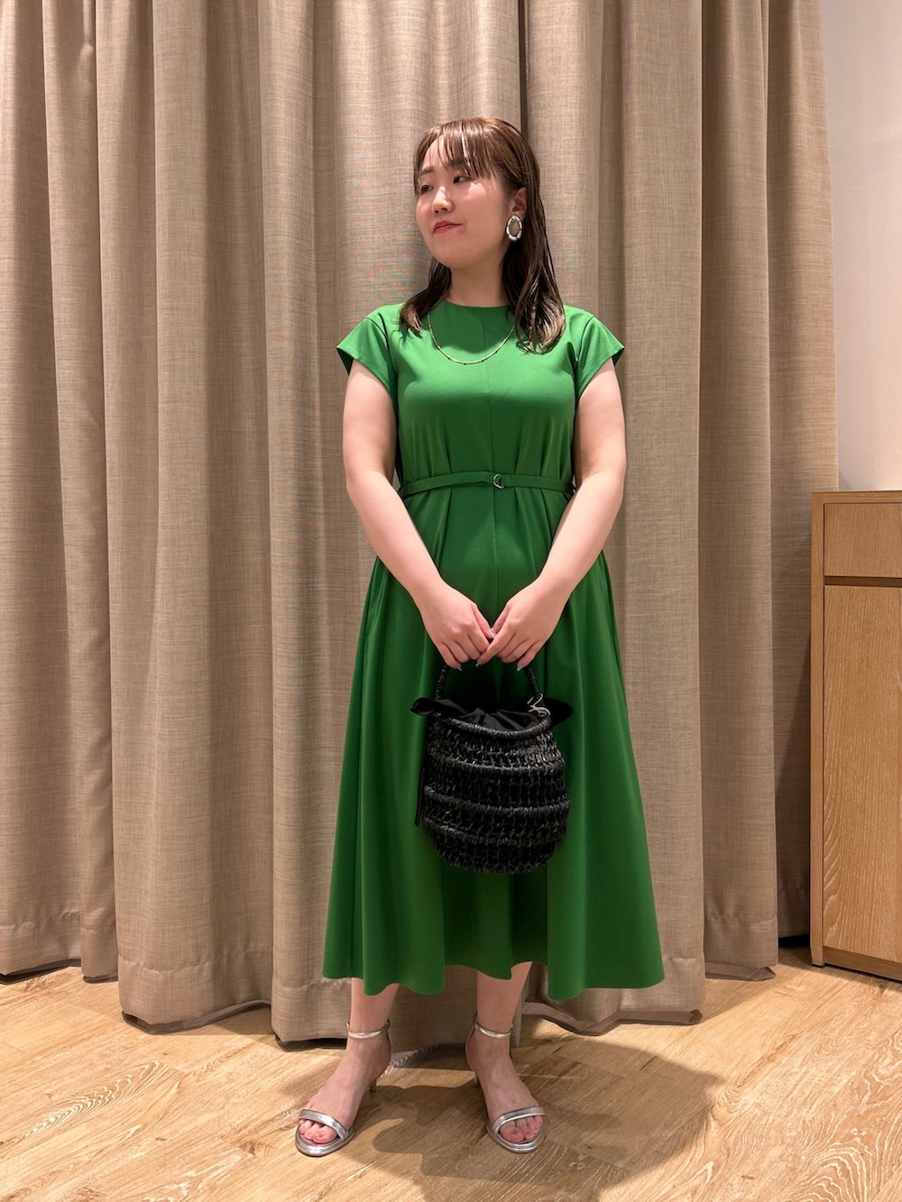 グリーン系のワンピース、ブラック系のかごバッグ、シルバー系のサンダルを着用したレディースの夏コーディネートの5枚目の写真