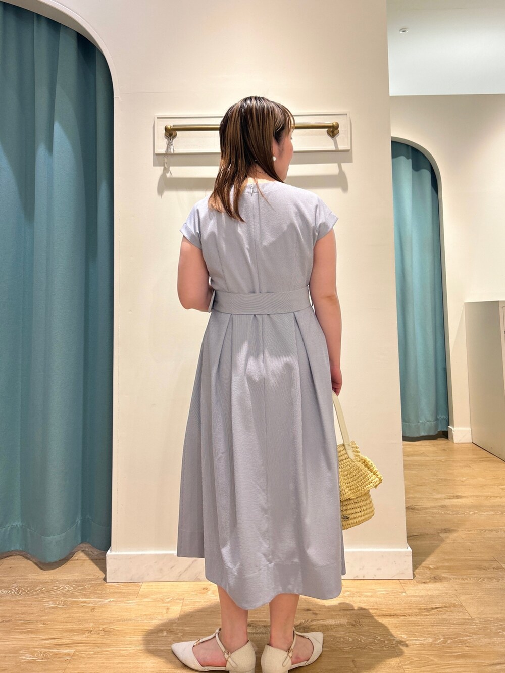 ブルー系のワンピース、ベージュ系のかごバッグ、シルバー系のネックレスを着用したレディースの夏コーディネートの4枚目の写真