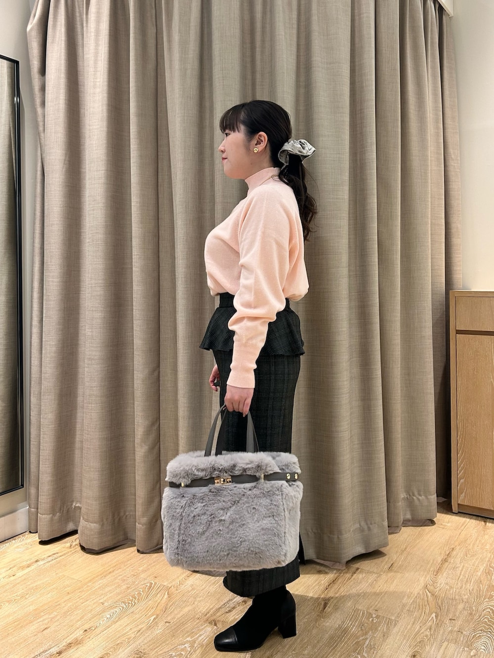 ピンク系のニット/セーター、ブラック系のスカート、ベージュ系のトートバッグを着用したレディースの冬コーディネートの2枚目の写真