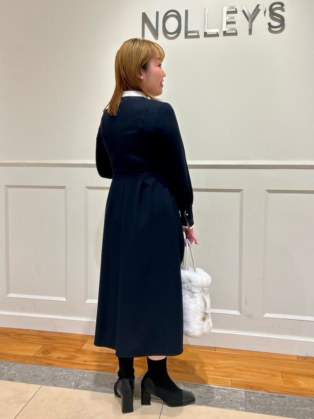 ブルー系のワンピース、ホワイト系のショルダーバッグ、ホワイト系のイヤリングを着用したレディースの冬コーディネートの3枚目の写真