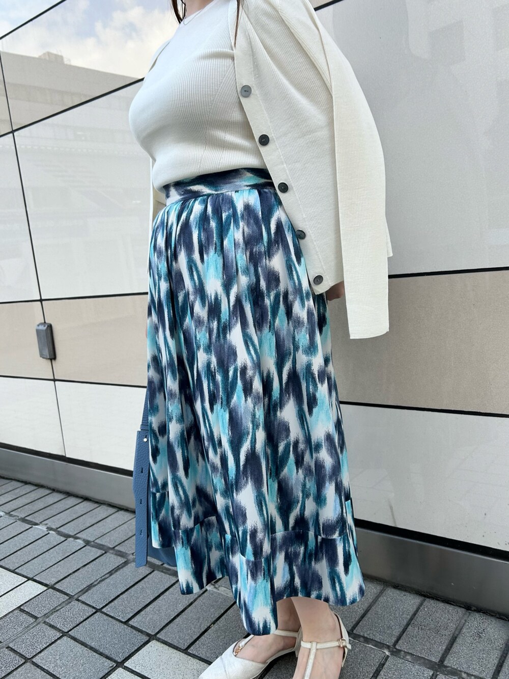 ホワイト系のカーディガン/ボレロ、ホワイト系のニット/セーター、ブルー系のスカートを着用したレディースの秋コーディネートの6枚目の写真