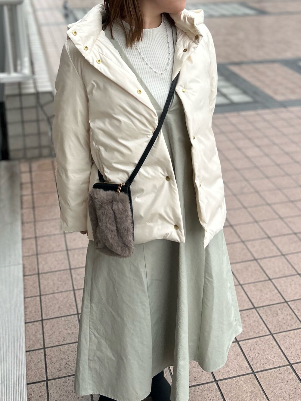 ホワイト系のダウンジャケット/コート、グレー系のワンピース、シルバー系のニット/セーターを着用したレディースの冬コーディネートの10枚目の写真