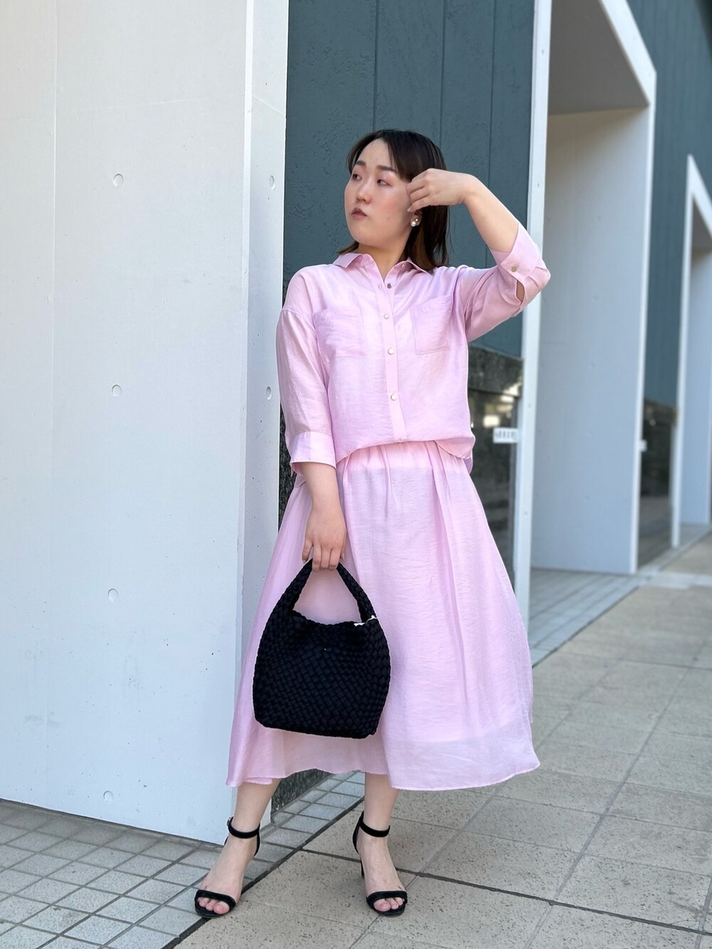 ピンク系のシャツ/ブラウス、ピンク系のスカート、ブラック系のショルダーバッグを着用したレディースの春コーディネートの2枚目の写真