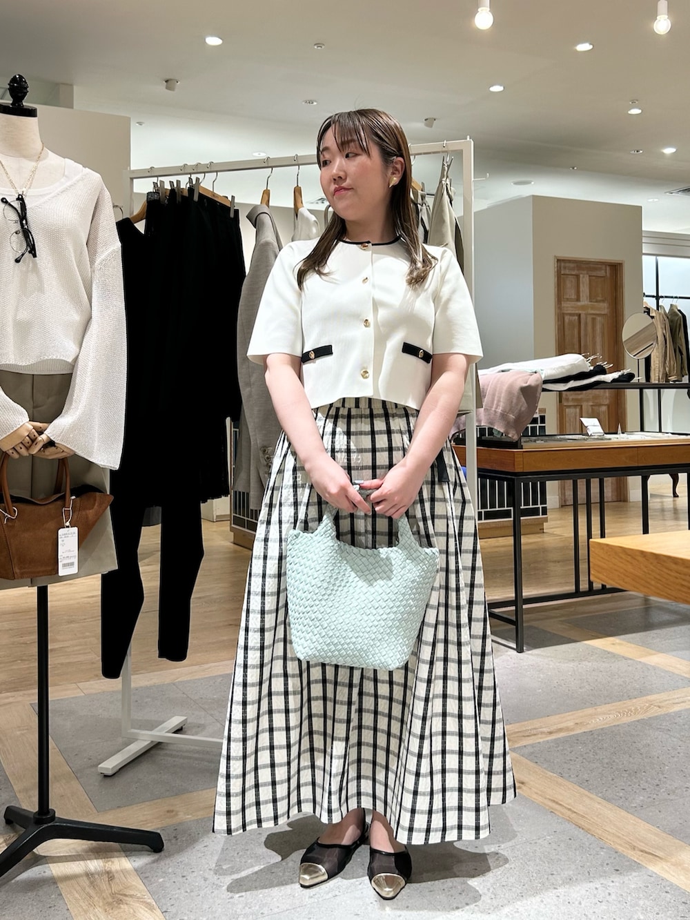 ホワイト系のノーカラージャケット、グリーン系のショルダーバッグ、ゴールド系のイヤリングを着用したレディースの夏コーディネートの5枚目の写真