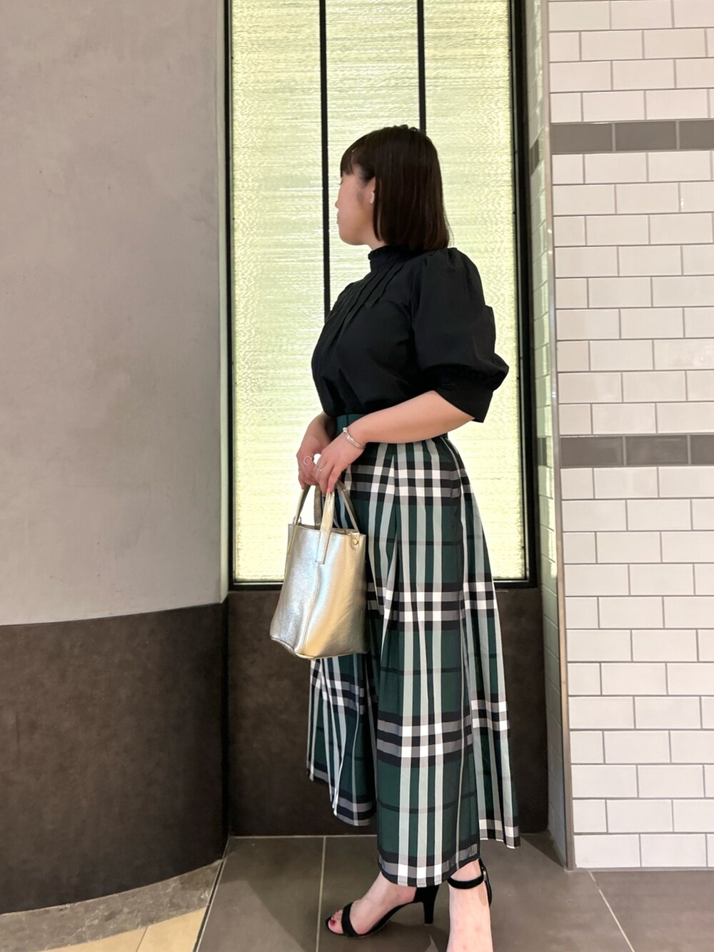 ブラック系のシャツ/ブラウス、グリーン系のスカート、ホワイト系のトートバッグを着用したレディースの夏コーディネートの3枚目の写真