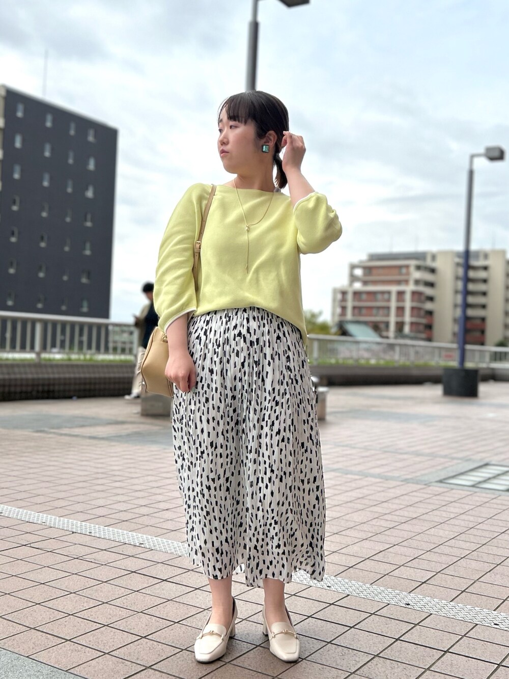 ホワイト系のスカート、ベージュ系のハンドバッグ、イエロー系のニット/セーターを着用したレディースの春コーディネートの5枚目の写真