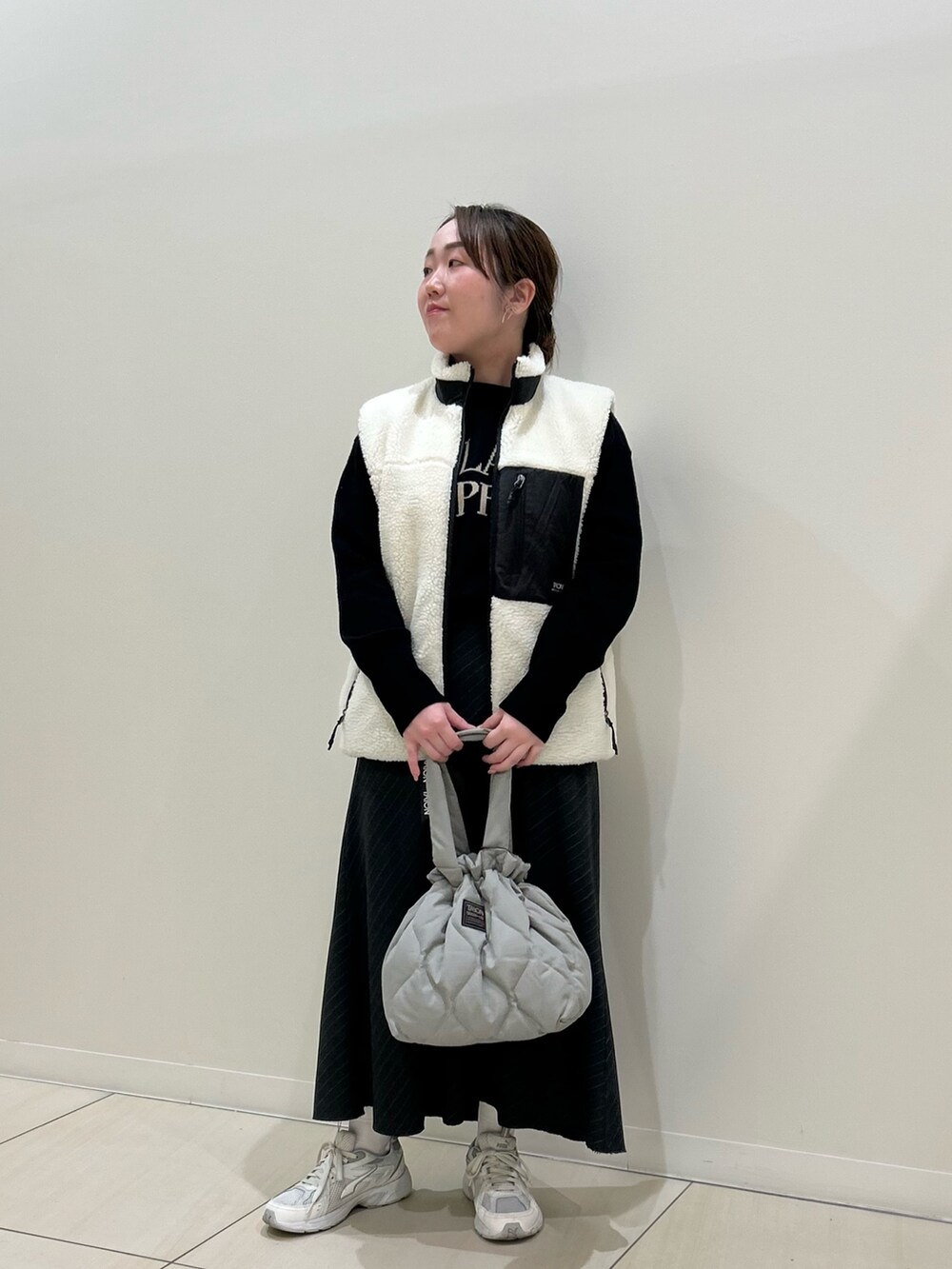 ホワイト系のダウンベスト、ブラック系のカーディガン/ボレロ、グリーン系のトートバッグを着用したレディースの冬コーディネートの9枚目の写真