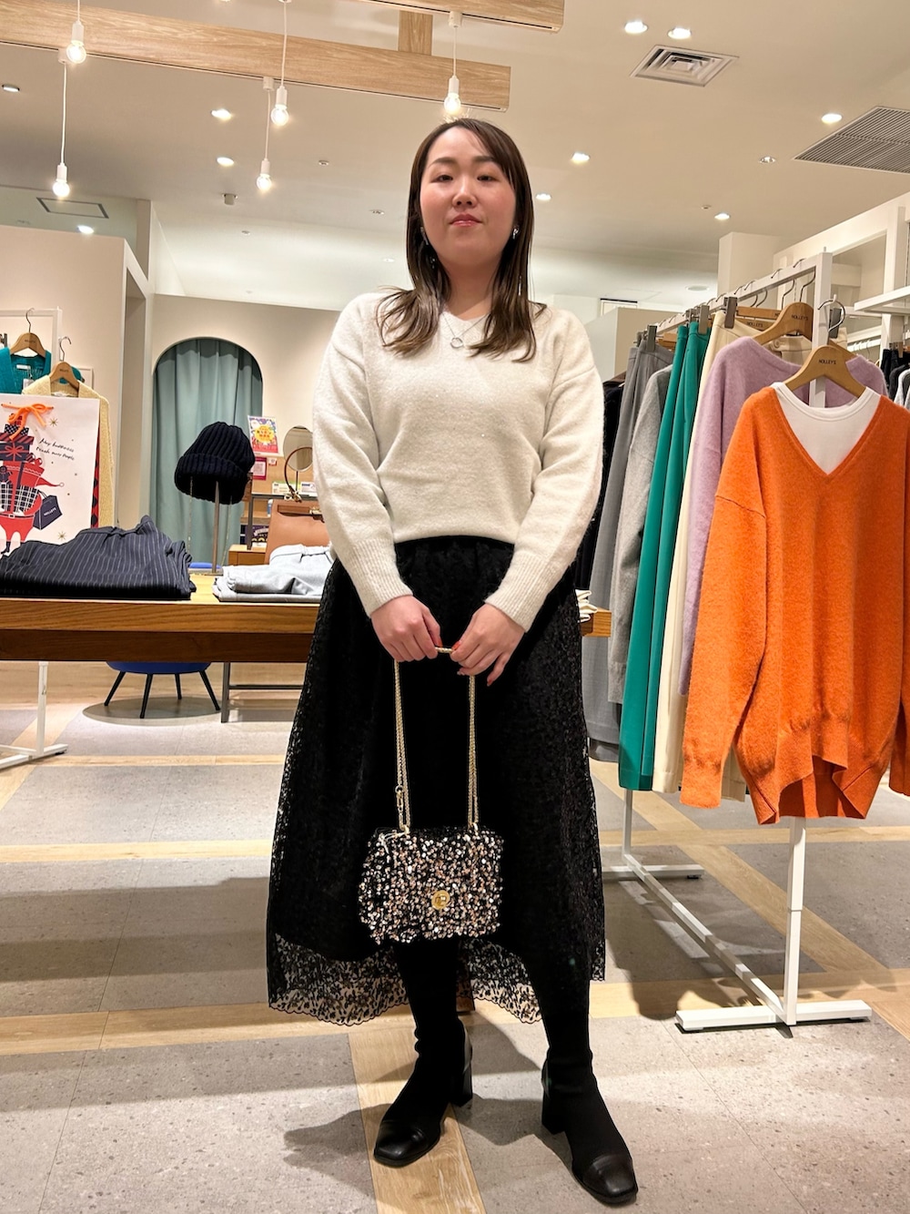 ホワイト系のニット/セーター、ブラック系のスカート、その他のショルダーバッグを着用したレディースの冬コーディネートの6枚目の写真