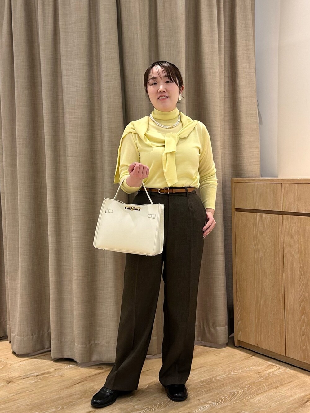 イエロー系のニット/セーター、イエロー系のカーディガン/ボレロ、ブラウン系のその他パンツを着用したレディースの秋コーディネートの6枚目の写真