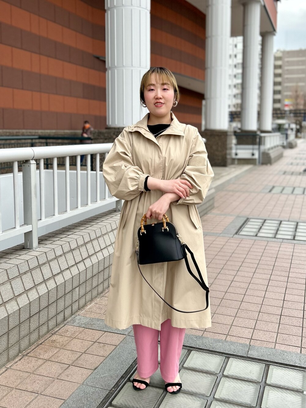 ベージュ系のその他アウター、ブラック系のニット/セーター、ピンク系のチノパンツを着用したレディースの春コーディネートの2枚目の写真