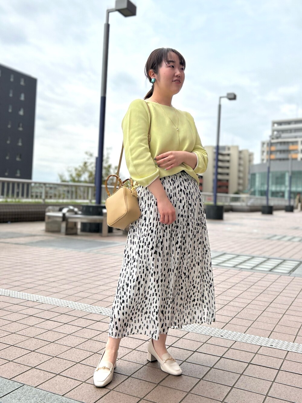 ホワイト系のスカート、ベージュ系のハンドバッグ、イエロー系のニット/セーターを着用したレディースの春コーディネートの8枚目の写真