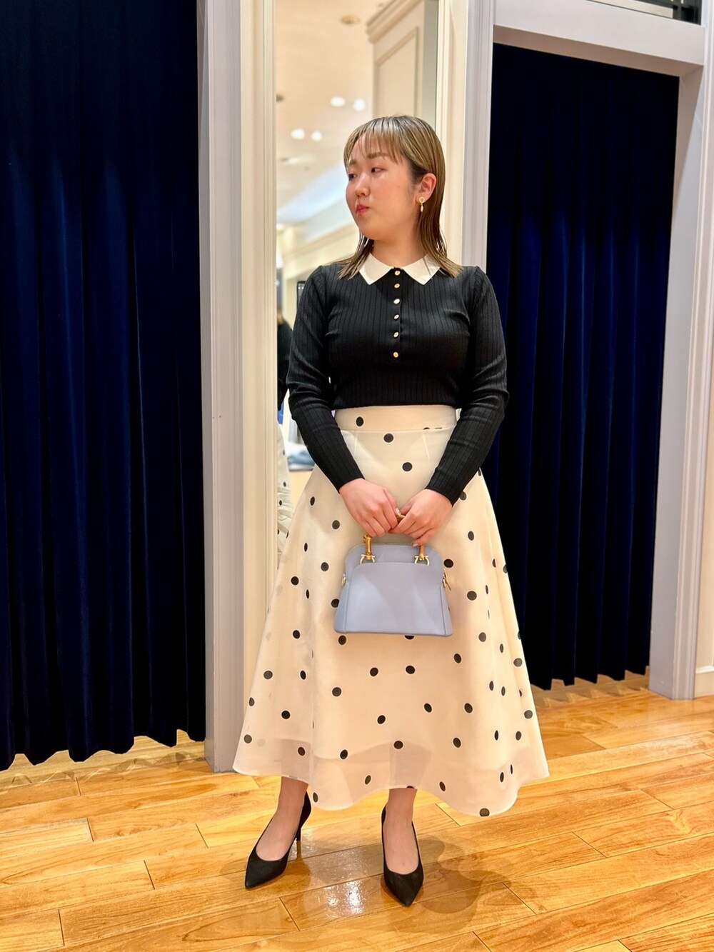 ブラック系のニット/セーター、ホワイト系のスカート、ブルー系のショルダーバッグを着用したレディースの冬コーディネートの7枚目の写真