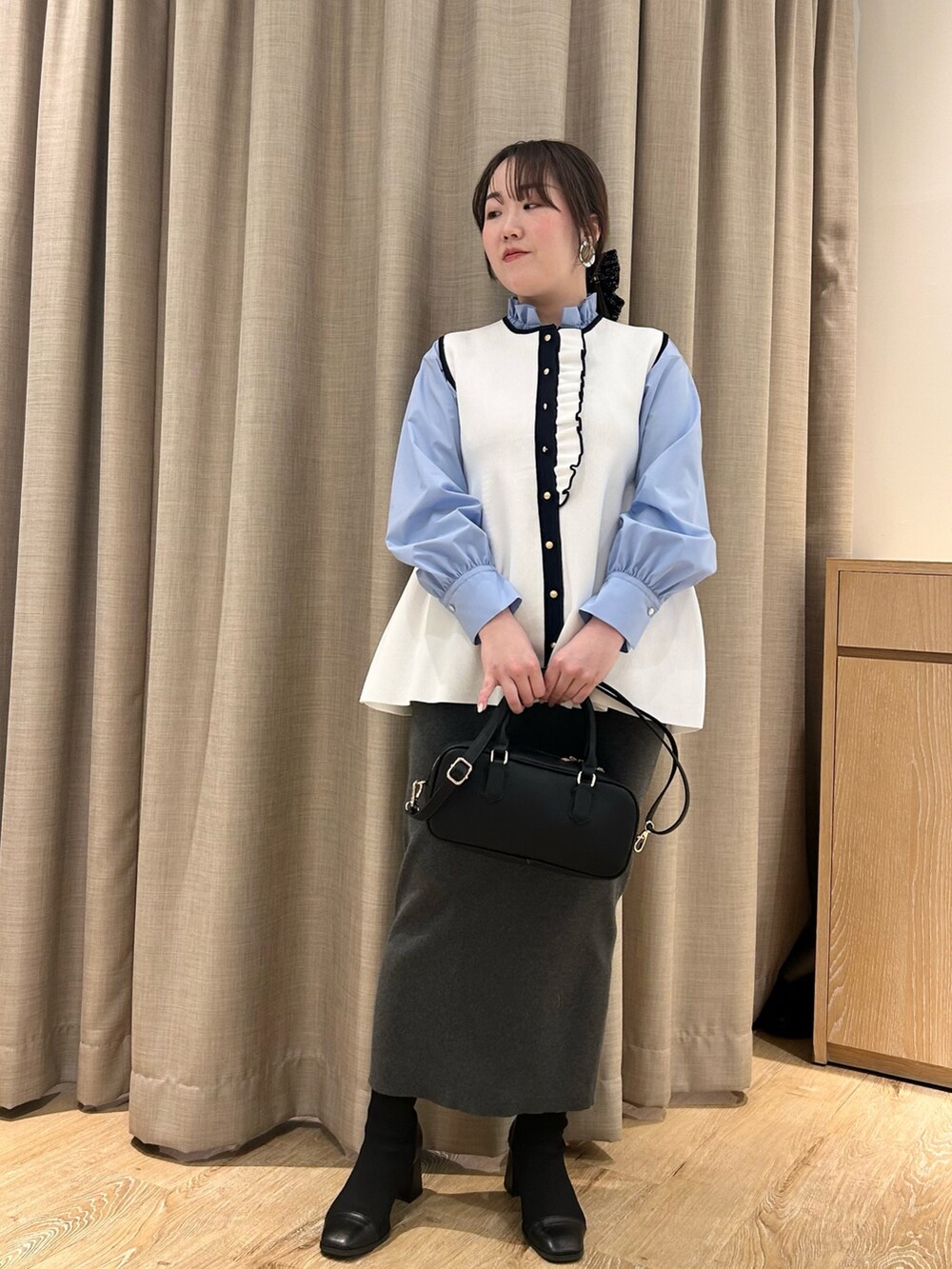 ホワイト系のベスト、ブルー系のシャツ/ブラウス、グレー系のスカートを着用したレディースの冬コーディネートの6枚目の写真