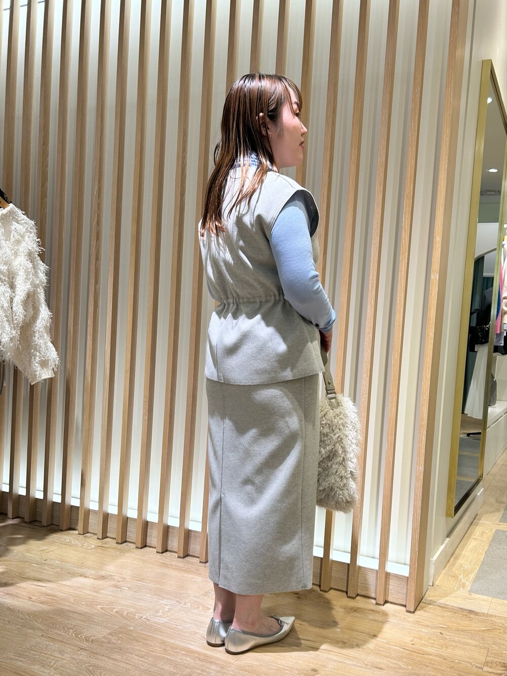 グレー系のベスト、グレー系のスカート、ブルー系のニット/セーターを着用したレディースの冬コーディネートの4枚目の写真