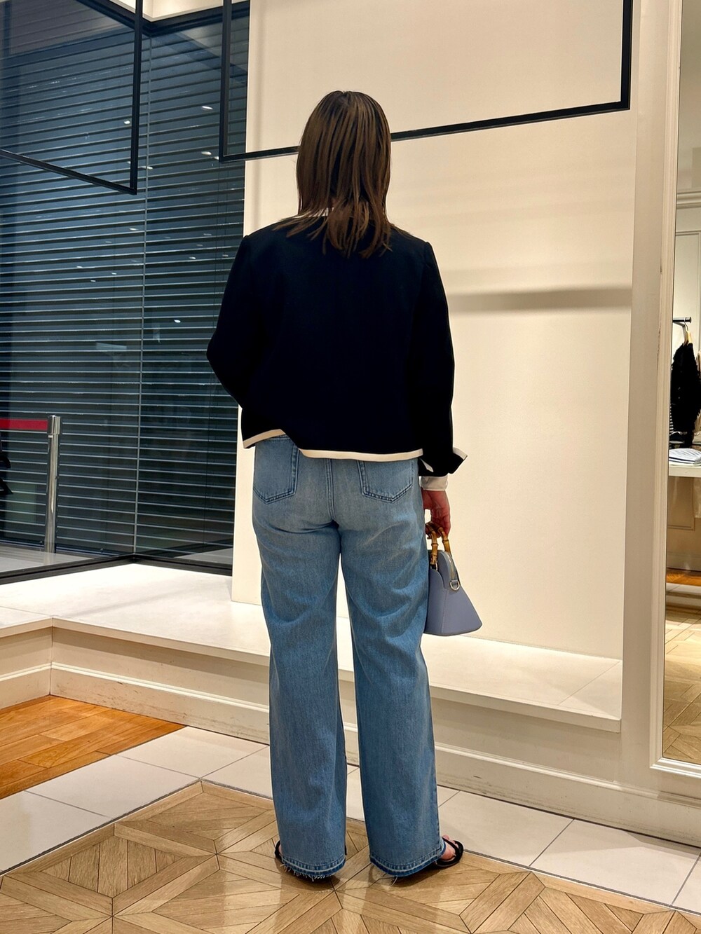 ブラック系のノーカラージャケット、ホワイト系のTシャツ/カットソー、ブルー系のデニムパンツを着用したレディースの冬コーディネートの5枚目の写真