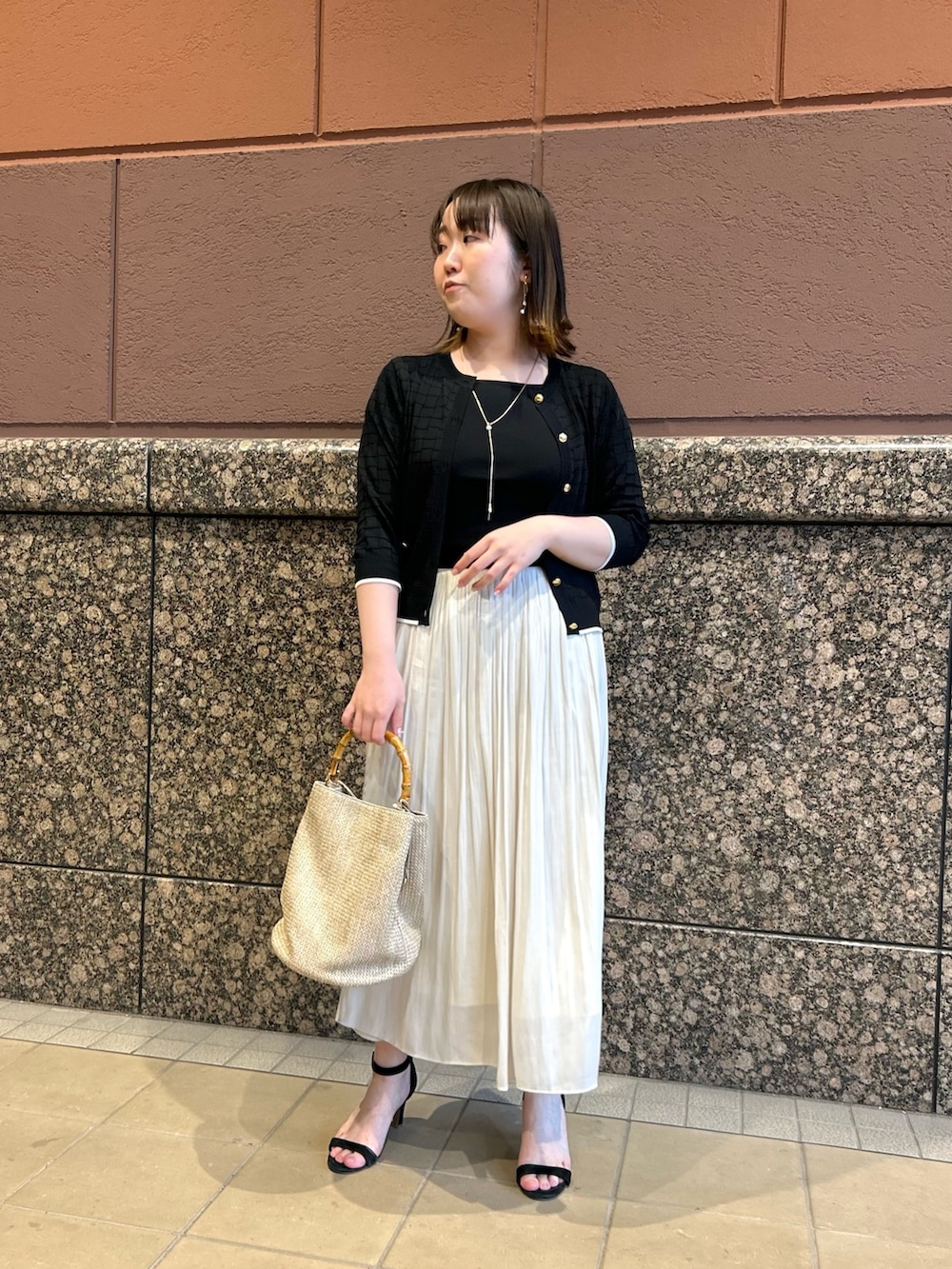 ブラック系のニット/セーター、ブラック系のカーディガン/ボレロ、ベージュ系のトートバッグを着用したレディースの春コーディネートの2枚目の写真