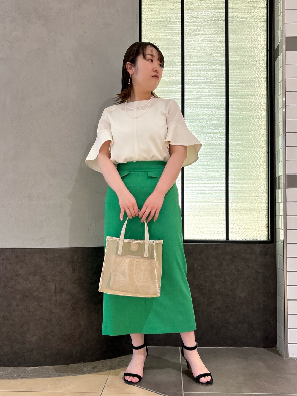 ベージュ系のトートバッグ、ホワイト系のシャツ/ブラウス、グリーン系のスカートを着用したレディースの春コーディネートの6枚目の写真