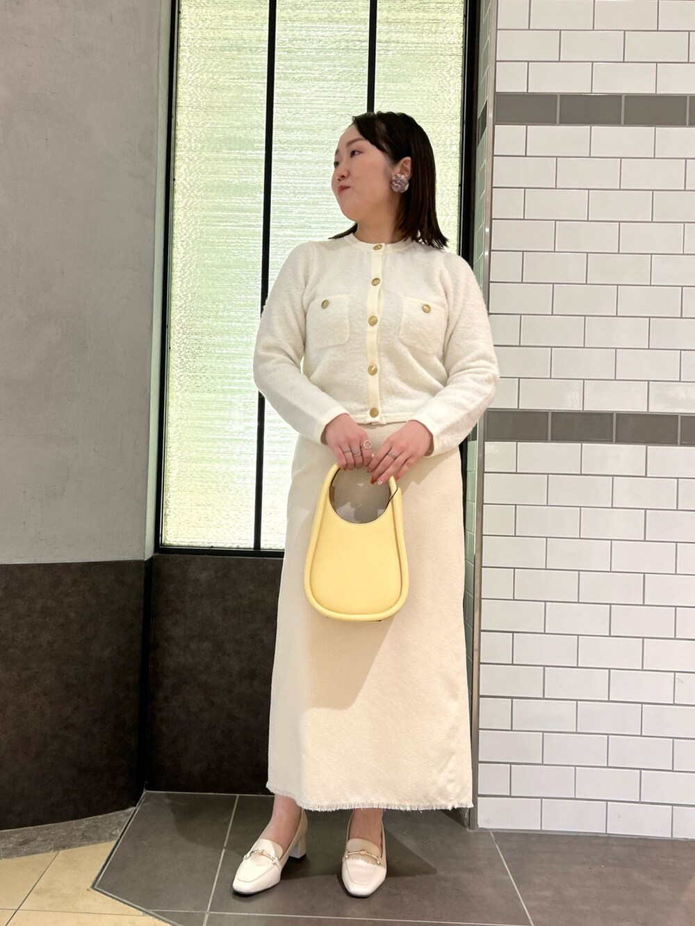 ホワイト系のカーディガン/ボレロ、ホワイト系のスカート、イエロー系のハンドバッグを着用したレディースの秋コーディネートの5枚目の写真