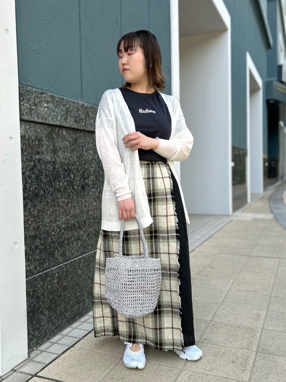 ホワイト系のカーディガン/ボレロ、ブラック系のスカート、シルバー系のバックパック/リュックを着用したレディースの春コーディネートの9枚目の写真