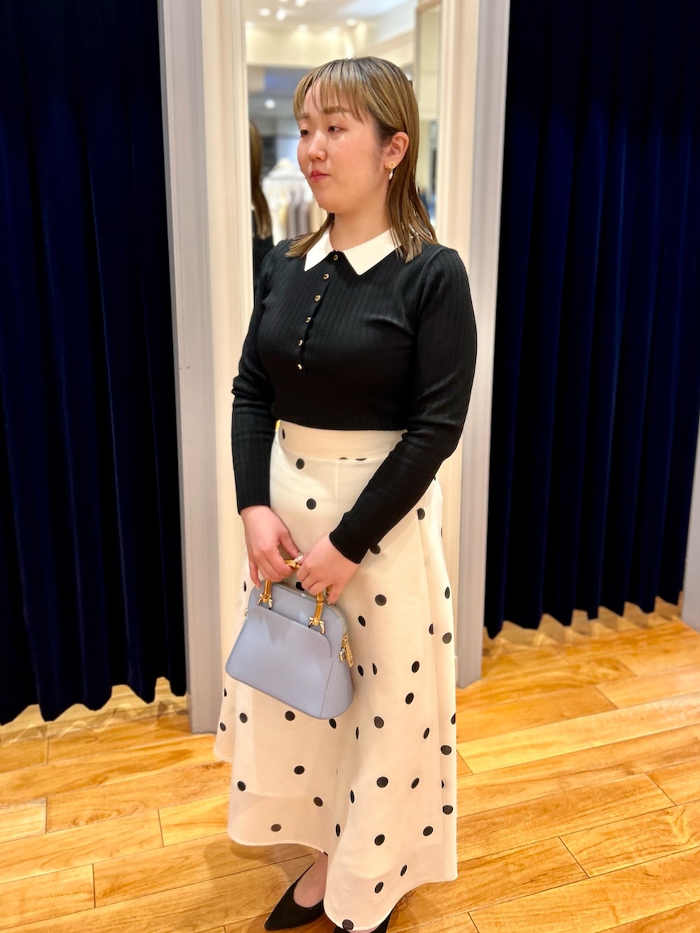 ブラック系のニット/セーター、ホワイト系のスカート、ブルー系のショルダーバッグを着用したレディースの冬コーディネートの9枚目の写真