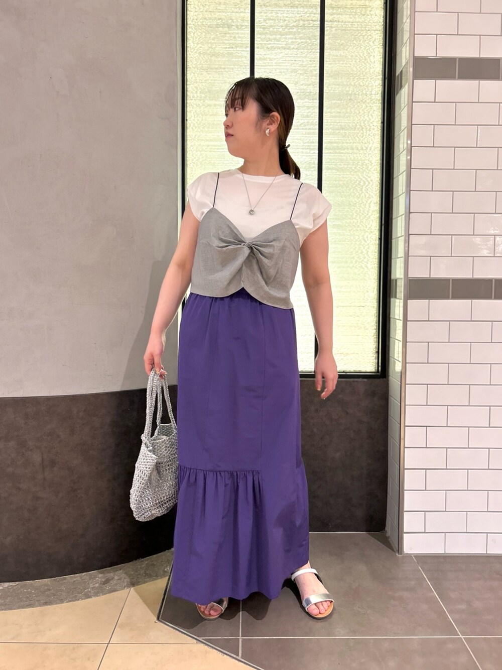 グレー系のTシャツ/カットソー、パープル系のスカート、シルバー系のバックパック/リュックを着用したレディースの夏コーディネートの6枚目の写真