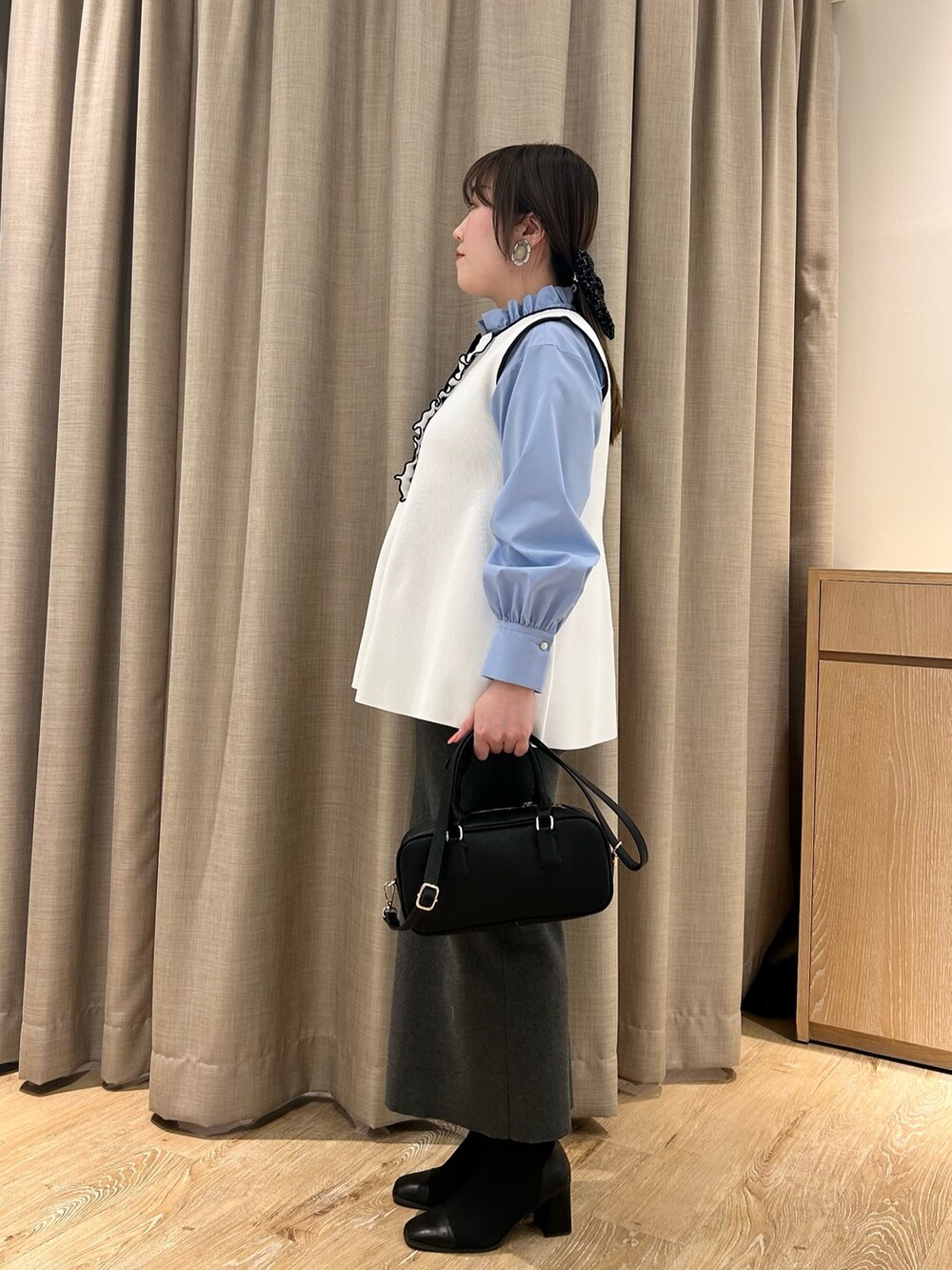 ホワイト系のベスト、ブルー系のシャツ/ブラウス、グレー系のスカートを着用したレディースの冬コーディネートの2枚目の写真