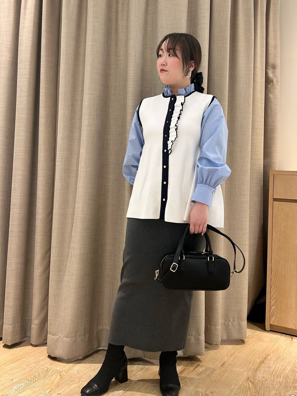 ホワイト系のベスト、ブルー系のシャツ/ブラウス、グレー系のスカートを着用したレディースの冬コーディネートの7枚目の写真