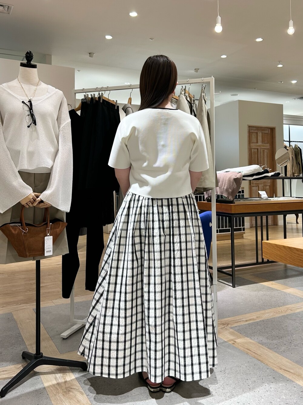 ホワイト系のノーカラージャケット、グリーン系のショルダーバッグ、ゴールド系のイヤリングを着用したレディースの夏コーディネートの3枚目の写真