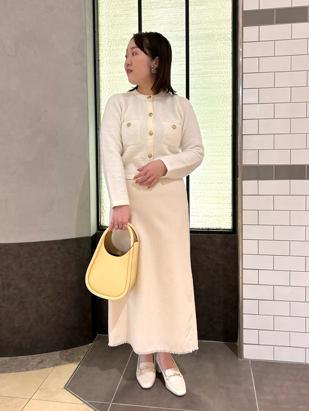 ホワイト系のカーディガン/ボレロ、ホワイト系のスカート、イエロー系のハンドバッグを着用したレディースの秋コーディネートの7枚目の写真