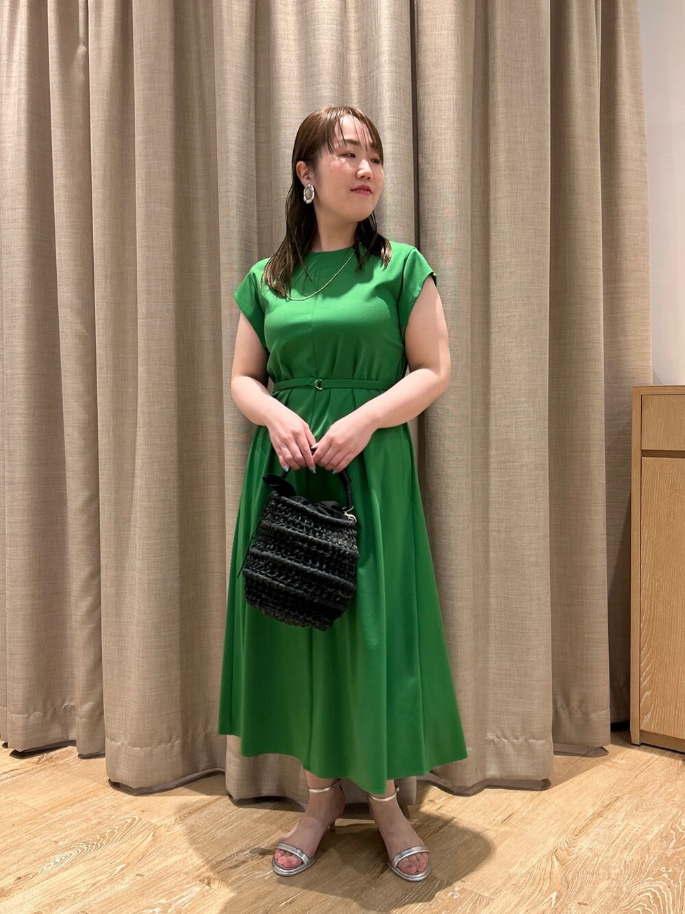 グリーン系のワンピース、ブラック系のかごバッグ、シルバー系のサンダルを着用したレディースの夏コーディネートの6枚目の写真