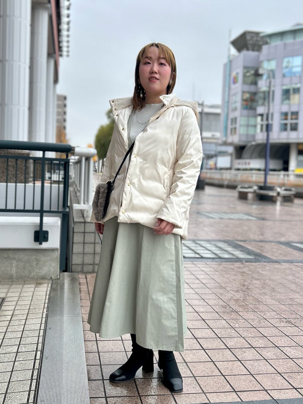 ホワイト系のダウンジャケット/コート、グレー系のワンピース、シルバー系のニット/セーターを着用したレディースの冬コーディネートの7枚目の写真