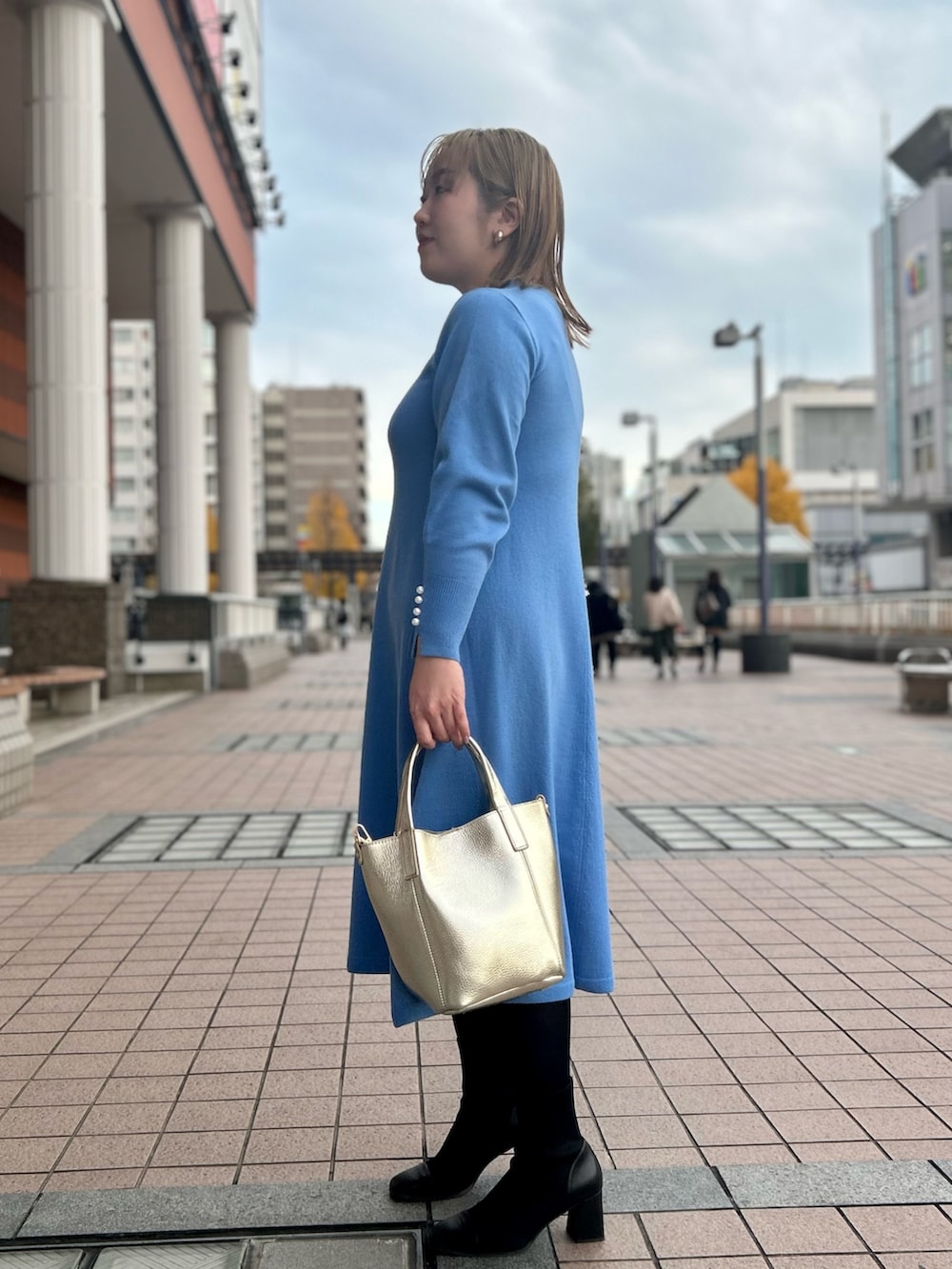 ブルー系のワンピース、ゴールド系のトートバッグ、ゴールド系のイヤリングを着用したレディースの冬コーディネートの7枚目の写真