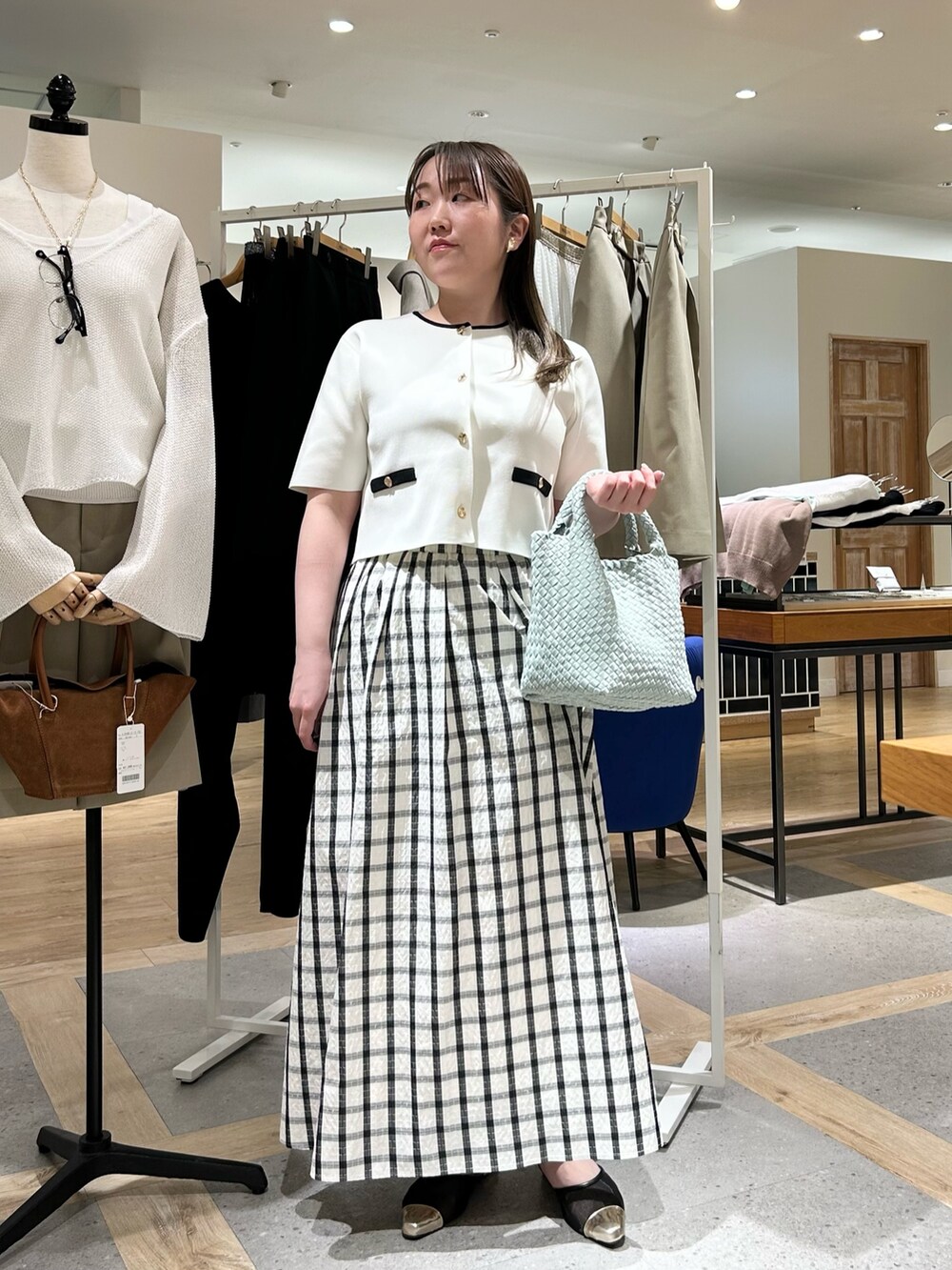 ホワイト系のノーカラージャケット、グリーン系のショルダーバッグ、ゴールド系のイヤリングを着用したレディースの夏コーディネートの7枚目の写真