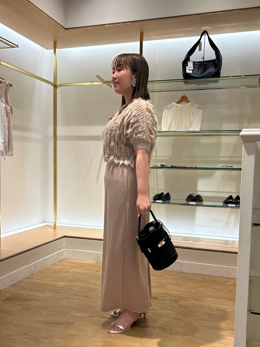 ベージュ系のニット/セーター、ベージュ系のスカート、ブラック系のショルダーバッグを着用したレディースの夏コーディネートの2枚目の写真