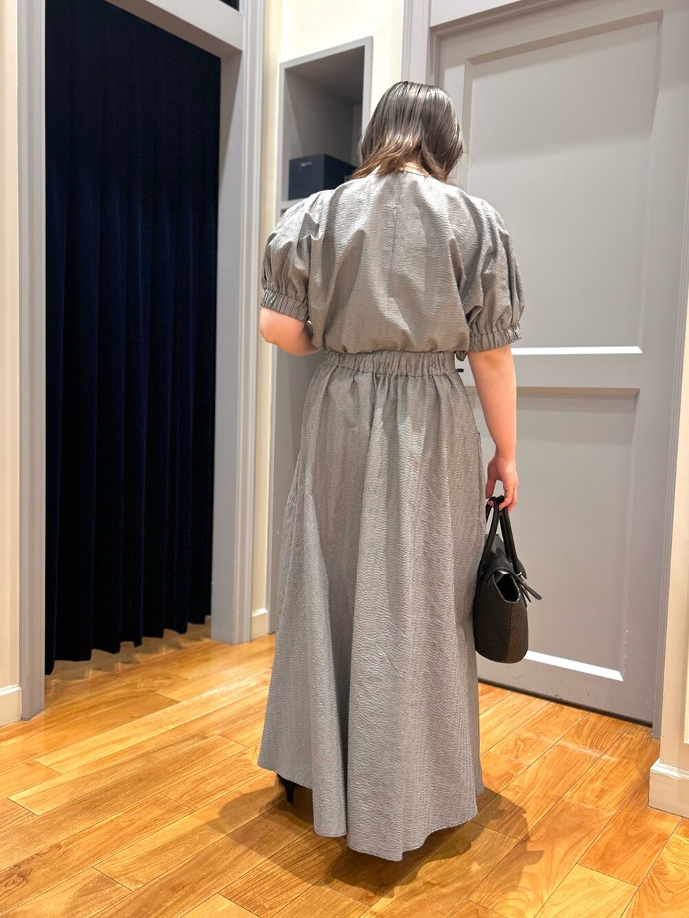 グレー系のシャツ/ブラウス、グレー系のスカート、ブラック系のかごバッグを着用したレディースの夏コーディネートの9枚目の写真