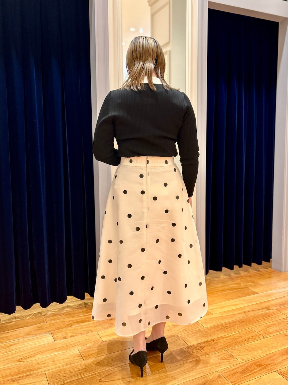 ブラック系のニット/セーター、ホワイト系のスカート、ブルー系のショルダーバッグを着用したレディースの冬コーディネートの4枚目の写真