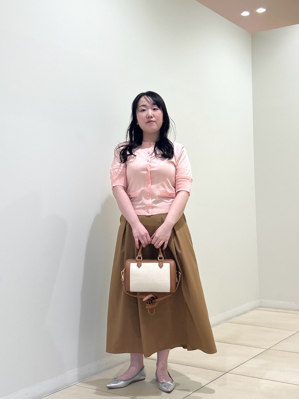 ピンク系のカーディガン/ボレロ、イエロー系のスカート、ブラウン系のボストンバッグを着用したレディースの夏コーディネートの6枚目の写真